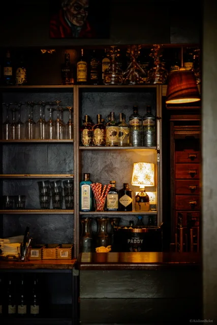 The back bar shelves at Guys Bar with bottles and warm lighting
