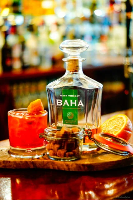 A cocktail served beside a Baha Irish whiskey decanter at the bar