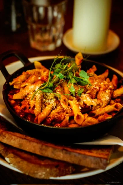 Pasta served in a black pan with fresh herbs at Guys Bar